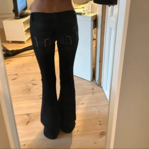Svarta bootcut jeans med nitar - Snygga svarta jeans med bootcut-modell och låg midja. Jeansen har coola detaljer med nitar på bakfickorna och klassisk femficksdesign. Materialet är stretchigt jeans för en bekväm passform. Perfekta för dig som gillar en trendig och stilren look. Midjemåttet rakt över är: ca 33cm men stretchiga så passar upptill 38/39cm, grenen är 17cm hög, innerbenslängden är ca 81cm😊