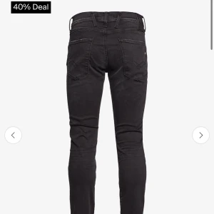 Svarta Replay Anbass jeans slim fit - Säljer ett par svarta Replay Anbass jeans med slim passform. Jeansen har klassisk femficksdesign, bälteshällor och snygga detaljer på bakfickorna. Materialet är stretchigt jeans för extra komfort och sitter tajt längs benen.