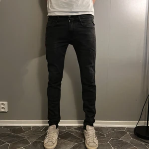 Svarta Replay Anbass  - Svarta Replay Anbass jeans i slim fit med klassisk femficksdesign och diskret Replay-logga vid fickan. Jeansen har smal passform, låg midja och är tillverkade i stretchigt bomullsmaterial för en bekväm känsla. Perfekta för dig som gillar en slimmad look.