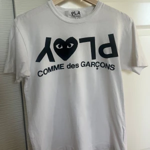 Vit Comme des Garçons Play t-shirt - Snygg vit t-shirt från Comme des Garçons Play med ikoniskt svart tryck och hjärtdesign med ögon på bröstet. Klassisk rund hals och korta ärmar. Pris kan diskuteras!🤍