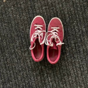 Röda converse - Säljer ett par röda Converse sneakers i mocka med vit stjärna på sidan och vita snören. Skorna har platt sula och rund tå, samt klassisk Converse-mönstrad undersida. Perfekta för dig som vill sticka ut med färg och cool detalj❤️