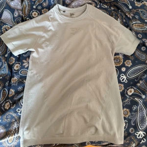 Gymshark onyx - Säljer en ljusgrå t-shirt från Gymshark med diskret logga på bröstet. T-shirten är kortärmad och tillverkad i ett lätt och ventilerande polyestermaterial, perfekt för träning. Snygg, enkel design med rund hals och stretchig passform. Storlek M. Det är en compression shirt från gymshark.