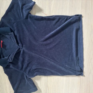 Mörkblå piké från RYVLS - Mörkblå piké från RYVLS med klassisk krage och korta ärmar. Tillverkad i mjuk frotté som ger en skön och avslappnad känsla. Perfekt för dig som gillar en enkel men stilren look.