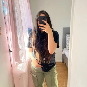 Gröna cargopants med raka ben - Säljer ett par gröna cargopants med raka ben och stora fickor på sidorna. Byxorna har normal passform och stängs med knapp och dragkedja. Perfekta för en chill och avslappnad stil.