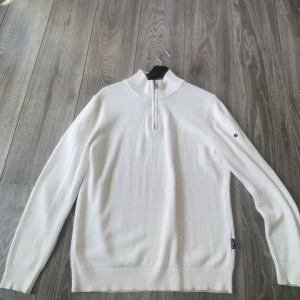 Vit stickad half zip från Stone Island - Snygg vit stickad tröja från Stone Island med half zip och grå detaljer på insidan av kragen. Långärmad modell med ribbad struktur och svarta knappar på ena ärmen. Perfekt för dig som gillar clean och stilren look. tyvär tappat bort den ikoniska etiketten på armen så därför är den billigare. köpt på NK en gång i tiden av farsan