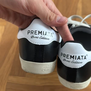 Premiata  sneakers  - Svartvita skor från Premiata med vit logga på sidan, snören och kontrasterande vit häl. Klassisk låg modell med rund tå och stilren design. Nästintill helt nya. Kvitto och box finns. 