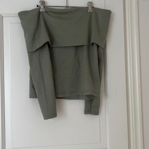 Grön offshoulder topp från Stockh LM - Snygg grön offshoulder topp från Stockh LM i mjuk bomull. Toppen har långa ärmar och en bred kant upptill som ger en cool och avslappnad look. Perfekt att styla med jeans eller kjol för en trendig vibe.