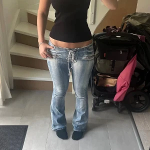 Lågmidjade bootcut jeans med snörning - Säljer mina ursnygga lowwaist jeans som tyvärr inte längre kommer till användning då de blivit lite för små för mig🥲stretchigt material. Visst slitage på snöret längst ut men annars i mycket bra skick. 
