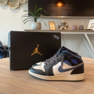 Nike Air Jordan 1 Mid svart/blå/vit - Nike Air Jordan 1 Mid sneakers i svart, blått och vitt skinn. Klassisk siluett med blå swoosh, svarta snören och perforerad tå. Ikonisk Jordan-logga på sidan och tungan. Perfekta för dig som gillar streetwear och vill sticka ut. Ny pris 2499kr säljer för 399😮‍💨