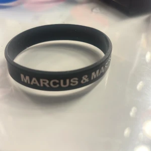 Marcus & Martinus svart silikonarmband - Svart silikonarmband med texten 'MARCUS & MARTINUS' i vitt. Perfekt accessoar för fans som vill visa sitt stöd för duon. Armbandet är flexibelt och bekvämt att bära hela dagen. !!pris kan diskuteras!!