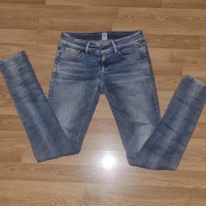 Replay jeans w26 L30 - Snygga blå skinny jeans med lätt slitna detaljer och en liten reva på ena knät. Jeansen har klassisk femficksdesign, dragkedjegylf och bälteshällor. Perfekta för en avslappnad och trendig look.