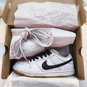 Nike SB Dunk Low Vit Svart Storlek 44 – Klassiska Skate Sneakers - Klassiska Nike SB Dunk Low i vit/svart, storlek 44. Använda men i bra skick – tidlös sneaker för både skate och vardag. Lite slitna på yttersula vid hälen Extra vita skosnören medföljer men de är lite slitna.             Pris diskuterbart vid snabba affärer! Finns mer på min profil.                                
