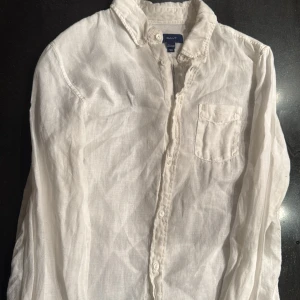 Vit linneskjorta från Gant - Vit skjorta från Gant i svalt linne med klassisk krage, bröstficka och knappar framtill. Perfekt för dig som gillar en clean och stilren look. Långärmad och med diskret broderad logga på fickan. Pris kan diskuteras 