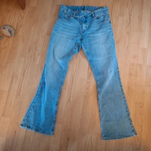Bootcut jeans med spänne - Säljer ett par ljusblå jeans med klassisk bootcut passform med coolt spänne. Jag har sytt in midjan, så passar storlek L, syns på sista bilden 