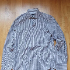 Rutig skjorta från Jack & Jones - Snygg rutig skjorta från Jack & Jones Premium i svart och vitt. Skjortan har klassisk krage, långa ärmar och knäppning framtill. Tillverkad i praktisk bomull. Perfekt för dig som gillar stilrena och tidlösa plagg. Väldigt bra skick.