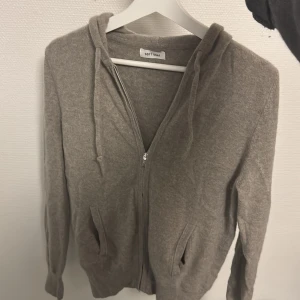 Beige hoodie i kashmir från Soft Goat - Mysig beige hoodie från Soft Goat i lyxig kashmir. Tröjan har dragkedja framtill, huva med snörning och två fickor. Perfekt för dig som vill ha en stilren och skön look med premiumkänsla. Denna tröjan e riktigt grisch!