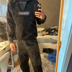 Svart fleece-tröja från Napapijri S - Svart fleece-tröja från Napapijri med stor logga på bröstet och half zip-dragkedja. Tröjan har lång ärm och är perfekt för kyliga dagar. Mjuk och skön insida, klassisk passform och stilren look.