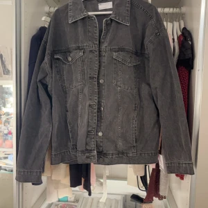 Svart jeansjacka från ASOS DESIGN - Säljer en svart jeansjacka från ASOS DESIGN i storlek M. Jackan har klassisk krage, knäppning framtill och två bröstfickor med lock. Snygg tvättad look och raka ärmar. Perfekt för dig som gillar en stilren och avslappnad vibe.