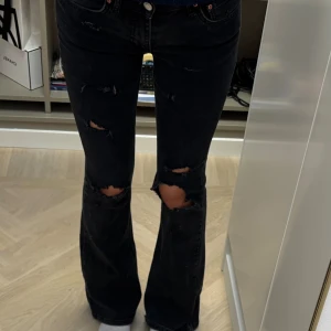 Svarta bootcut jeans med slitningar - Säljer ett par svarta jeans med bootcut-modell från Gina Tricot. Dem har hemmagjorda hål och längden är perfekt på mig som är 167cm<3