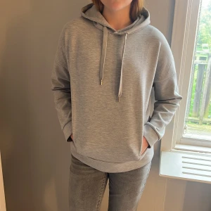 Grå hoodie från Lindex XS - Säljer en stilren grå hoodie från Lindex i storlek XS. Hoodien har huva med snörning, långa ärmar och en relaxed passform. Tunn och skönt material! Knappt använd!