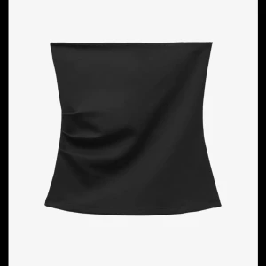 Svart bandeau tubtopp - Enkel och stilren svart bandeau tubtopp i stretchigt material. Toppen är axelbandslös och har en tight passform som sitter snyggt på kroppen. Perfekt att matcha med jeans eller kjol för en trendig look.