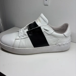 Svarta V@lentino skor  - Snygga V@lentino Garavani Open sneakers i vitt skinn med bred svart läderdetalj över mitten. Säljer dem på grund utav för liten storlek. Extremt fräscha skor över lag bra skick extremt passar bra under vintern. Hör av er vid frågor o funderingar (inte äkta)🥂Kom gärna med pris förslag💯