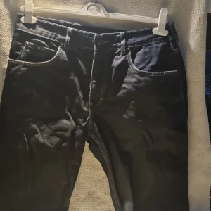 Svarta jeans från Blend Denim, stl 36 - Svarta jeans från Blend Denim med kontrastsömmar och klassisk femficksdesign. Jeansen har rak passform och är tillverkade i slitstarkt denimtyg. Perfekta för dig som gillar en enkel och stilren look.