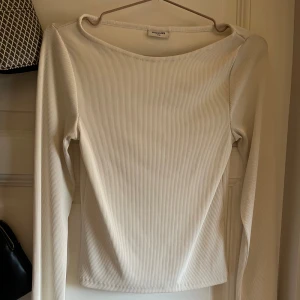 Vit ribbad långärmad topp Kappahl - Säljer en stilren vit långärmad topp från Kappahl. Toppen är ribbad och har en rund halsringning. Den är figurnära och tillverkad i ett stretchigt material som sitter snyggt på kroppen. Perfekt att matcha med jeans eller kjol för en clean look.