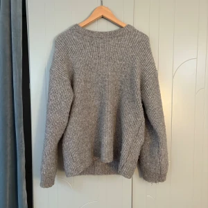 Grå stickad tröja från H&M Divided - Mysig grå stickad tröja från H&M Divided i storlek S. Tröjan har en rak passform, ribbstickat mönster och rund halsringning. Perfekt för lager-på-lager och chill dagar. Långärmad och riktigt skön att ha på sig.