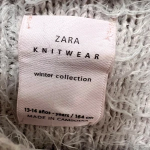 Ljusgrå fluffig stickad tröja Zara - Supermjuk och fluffig stickad tröja från Zara i ljusgrått. Tröjan har lång ärm, rund halsringning och ett snyggt ribbat mönster. Perfekt för kalla dagar när du vill vara både varm och trendig.