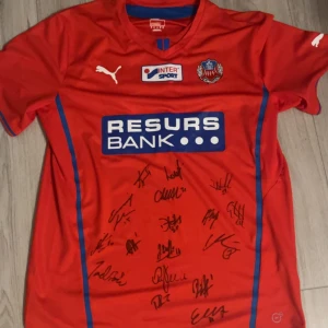 Signerad hif tröja  - Röd Helsingborgs IF fotbollströja från Puma med blå detaljer och tryckta sponsorer. Nummer 11 på ryggen och flera autografer på framsidan. 