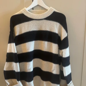Randig stickad tröja från H&M - Säljer en oversized stickad tröja från H&M i svart och vitt med breda ränder. Tröjan har rund halsringning, långa ärmar och är gjord i en mjuk ull- och kashmirblandning. Perfekt för kyliga dagar och superenkel att styla till jeans eller kjol.