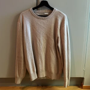 Beige stickad tröja från Zara - En stilren beige stickad tröja från Zara med rund halsringning och ribbade muddar. Perfekt för lager-på-lager och enkel att matcha med jeans. Mjuk och skön känsla, passar dig som gillar en klassisk look. Den är i mycket bra skick.