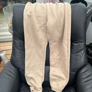 Beige mjukisbyxor med resår - Säljer ett par beige mjukisbyxor med resår i bensluten. Perfekta för chill dagar eller när du vill vara extra bekväm. Byxorna har en enkel och stilren look i mjukt material.