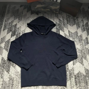 Mörkblå stickad hoodie  - Mörkblå stickad hoodie. Klassisk modell med huva och långa ärmar, perfekt för en chill och stilren look. Enkel design utan tryck eller detaljer, passar dig som gillar minimalistiskt mode.