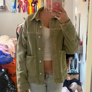 Olivgrön jeansjacka från Zara XS - Olivgrön jeansjacka från Zara i storlek XS. Jackan har klassisk krage, stora fickor framtill och knäppning med silvriga knappar. Snygg loose passform och tillverkad i bomull. Perfekt att slänga över en crop top och jeans.
