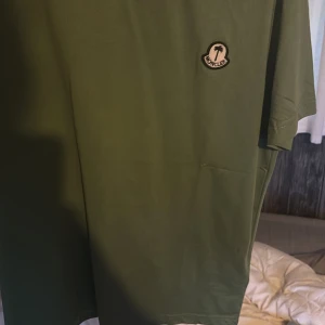 Moncler T-shirt som är i collab med palmangels  - Lyft din stil med den här exklusiva gröna T-shirten från det unika samarbetet mellan Moncler och Palm Angels. T-shirten kombinerar Monclers tidlösa känsla för kvalitet med Palm Angels rebelliska street-estetik – en perfekt balans mellan lyx och urban edge. Tillverkad i mjuk, premium bomull levererar tröjan både komfort och stil. Den distinkta gröna färgen ger ett fräscht och iögonfallande uttryck, medan det co-brandade trycket på bröstet markerar din känsla för detaljer och mode.