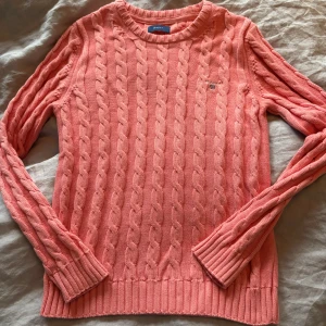 Corall kabelstickad tröja från GANT - Säljer en kabelstickadtröja i färgen corall från GANT. Storlek 170 se bild. Perfekt för dig som gillar klassisk och stilren look.