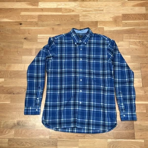 Blårutig skjorta från Ralph Lauren - Snygg blårutig skjorta från Ralph Lauren i slim fit-modell. Skjortan är tillverkad i stretchig bomull och har klassisk krage, knäppning framtill och broderad logga på bröstet. Passar dig som är runt 180cm lång perfekt 