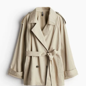 Beige trenchcoat med bälte från H&M (priset kan diskuteras vid snabb affär) - Stilren beige trenchcoat från H&M med klassisk krage, knytskärp i midjan och knappar framtill. Jackan har långa ärmar med snygga detaljer vid ärmslut och axelklaffar. Perfekt för dig som vill ha en tidlös och trendig look. Storlek M. Priset kan diskuteras vid snabb affär!