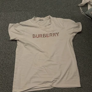 Vit Burberry t-shirt med broderad logga - Vit t-shirt från Burberry som är storlek S. Klassisk passform och rund halsringning. perfekt för en clean och stilren look.