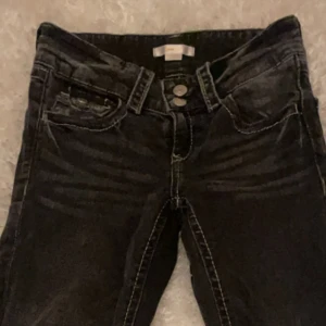Svarta jeans från Gina Tricot bootcut oxh low waist  - Snygga svarta jeans från Gina Tricot med bootcut ben, low waist och kontrastsömmar. Jeansen har dubbla silverfärgade knappar i midjan och klassiska fem fickor. Perfekta för dig som gillar en enkel men stilren look. Kontakta vid fler frågor!❤️