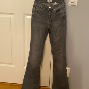 Grå bootcut jeans från ONLY, stl 32 - Snygga grå jeans från ONLY i bootcut-modell. Jeansen har klassisk femficksdesign, normal midja och är tillverkade i mjukt denimtyg. Perfekta för dig som gillar en retroinspirerad look med utsvängda ben.