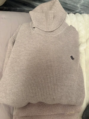 Beige polotröja från Morris Society XS - Aldrig använt! Säljer en ribbstickad beige polotröja från Morris Society i storlek XS . Tröjan har hög krage och en liten svart broderad logga på bröstet. Perfekt för dig som gillar klassisk och stilren look.