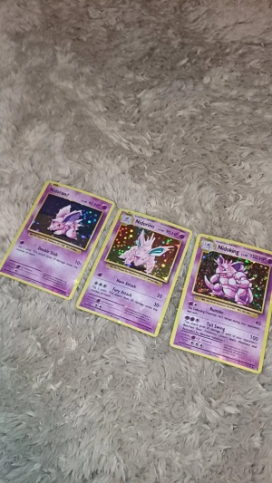 Pokémonkort: Nidoran♂, Nidorino & Nidoking (holo) - Samlartrio med holografiska Pokémonkort: Nidoran♂, Nidorino och Nidoking! Perfekt för dig som älskar Pokémon och vill boosta din samling med coola, glittrande kort. Passar både nya och erfarna samlare – gotta catch 'em all!