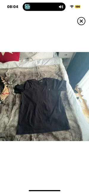 Svart t-shirt från Polo Ralph Lauren - Svart t-shirt från Polo Ralph Lauren med klassisk passform och liten broderad logga på bröstet. T-shirten har rund hals och korta ärmar, perfekt för en clean och stilren look. Materialet är mjuk bomull som känns skönt mot huden.