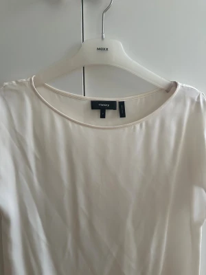 Vit blus från Theory - Supersnygg vit blus från Theory i silke med rund halsringning och korta ärmar. Blusen har en mjuk, slät yta och faller fint mot kroppen. Perfekt för dig som gillar minimalistisk och clean stil. Passar dig som vill ha en enkel men lyxig topp