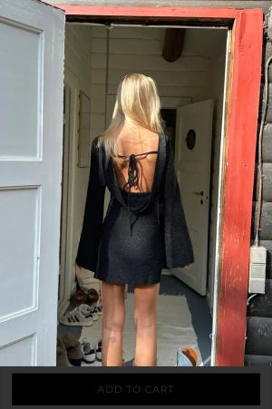 Svart glittrig kortklänning med öppen rygg - Supersnygg svart glittrig kortklänning med långa utsvängda ärmar och öppen rygg med snörning. 