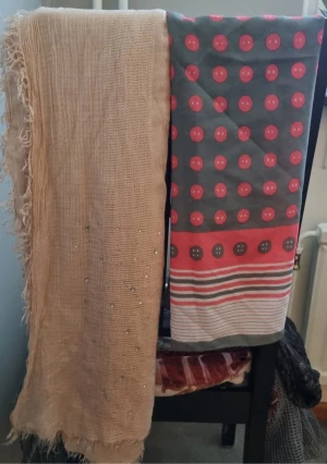 Beige glittrig halsduk & prickig sjal - Två snygga halsdukar! Ena är beige med glittriga detaljer och fransiga kanter, perfekt för att ge din outfit lite extra bling. Den andra är tunnare, grå med röda prickar och ränder i rött, grått och vitt, riktigt coolt mönster. Båda är långa och passar att svepa runt halsen.