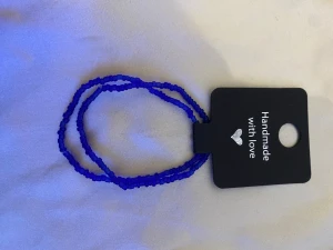 Handgjort blått pärlarmband - Snyggt handgjort armband med små blå pärlor. Armbandet är enkelt och stilrent, perfekt att matcha med andra smycken eller bära för sig själv. Färgen är intensivt blå och pärlorna är jämnt fördelade runt hela armbandet.